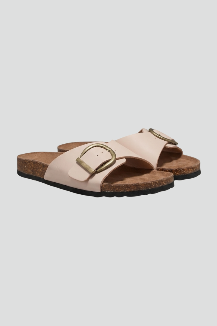 Beige flat sandals with bold buckle detail viewed from the side