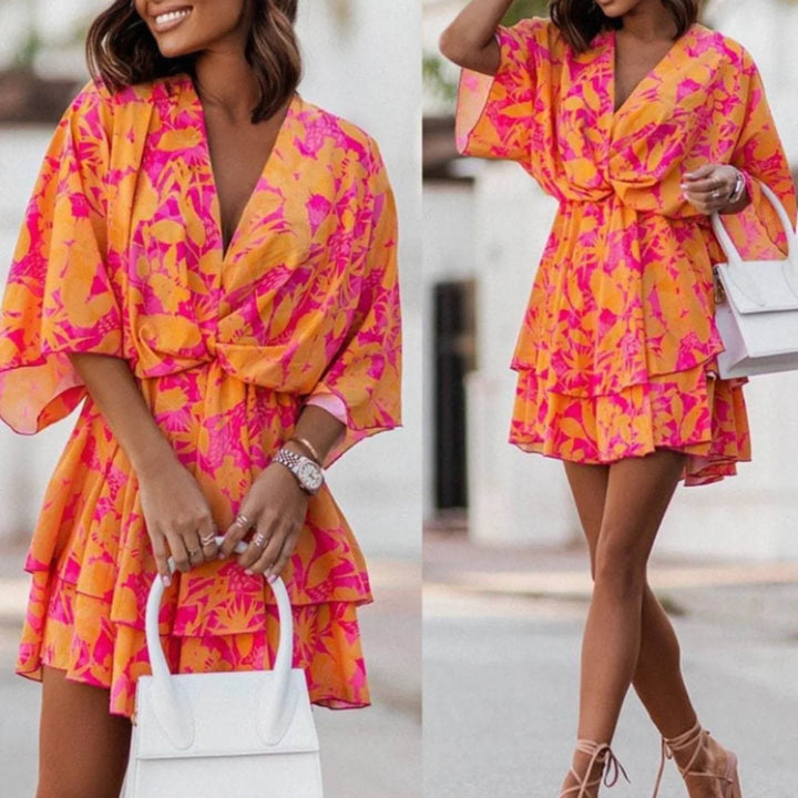 Close-up of model in an orange and pink floral V-neck mini dress outdoors
