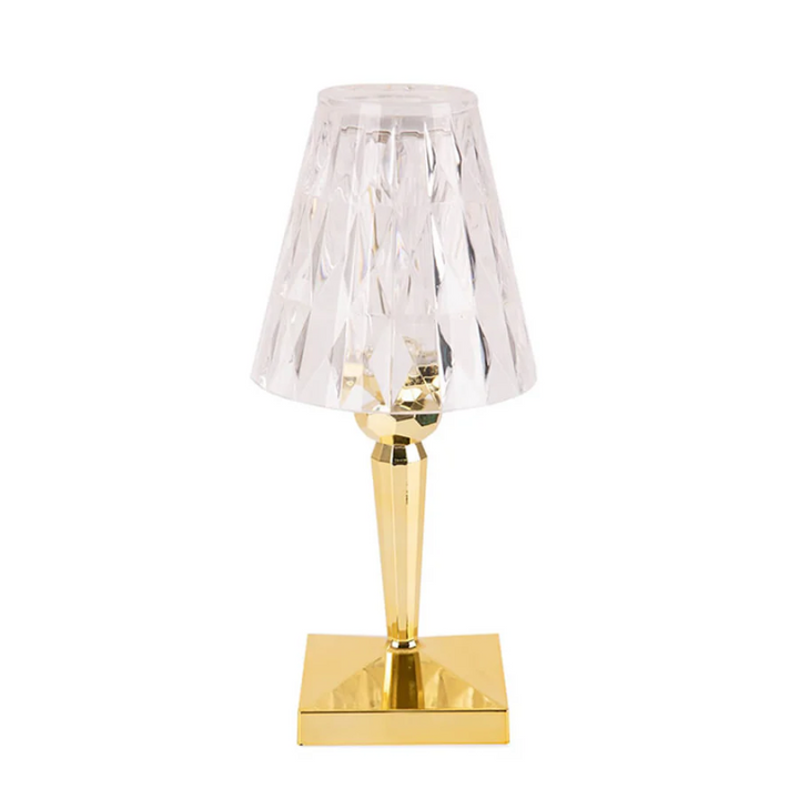 Clear crystal table lamp with gold base glowing warmly