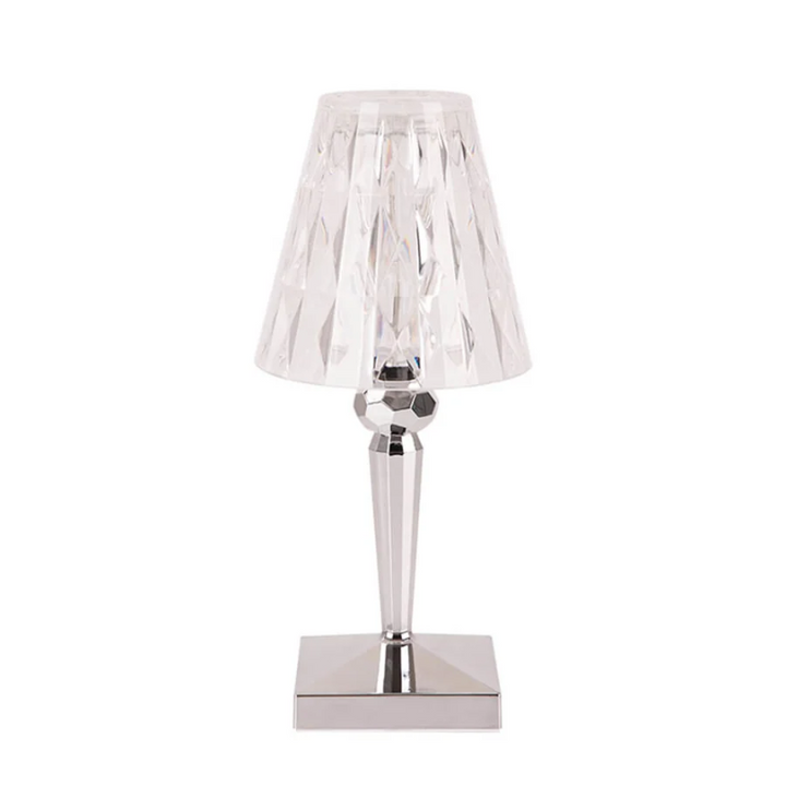 Clear crystal table lamp with silver base against a plain white background