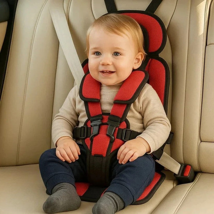 Young child safely secured in a red foldable travel car seat inside a vehicle.