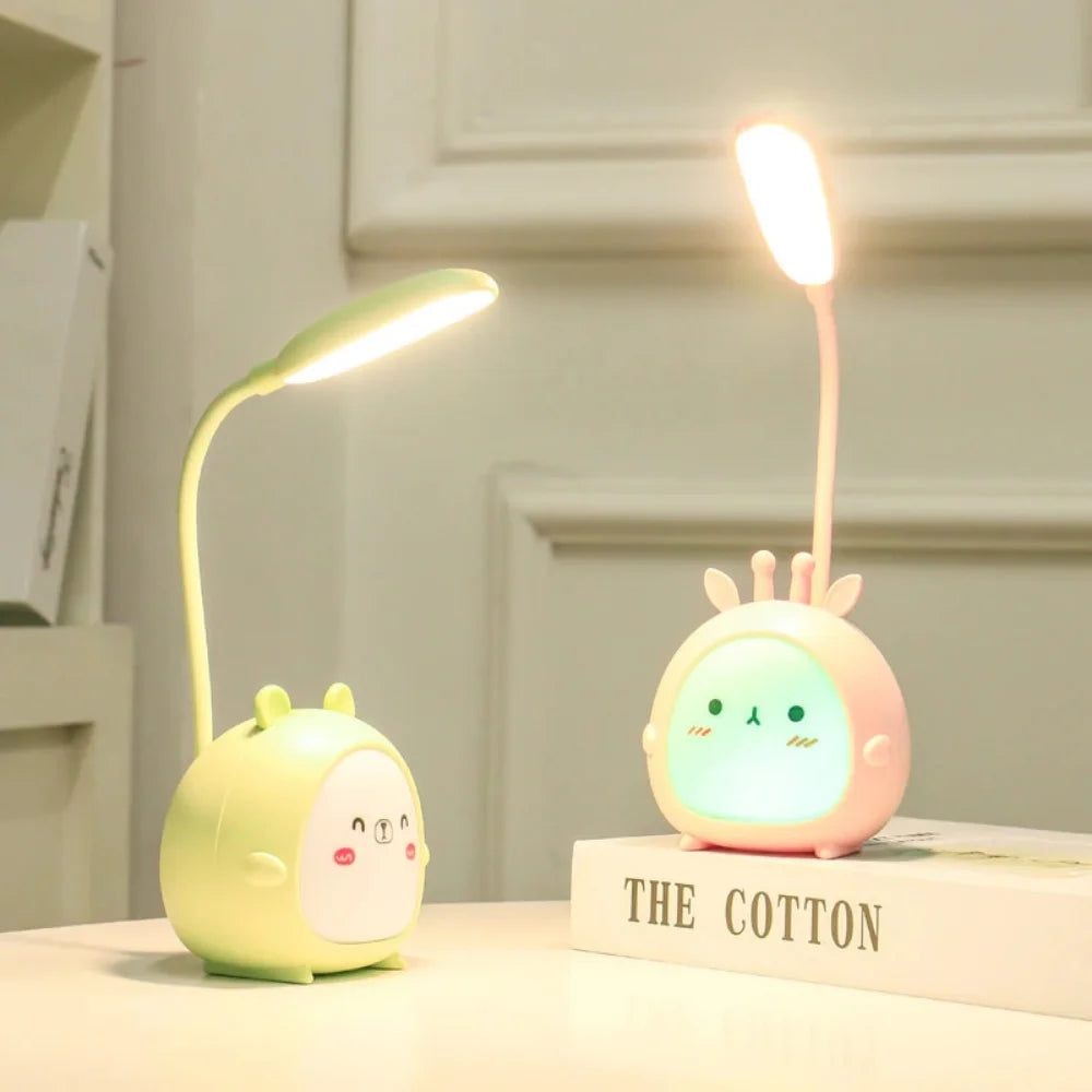 Green and pink cartoon deer children's reading lamps on a desk