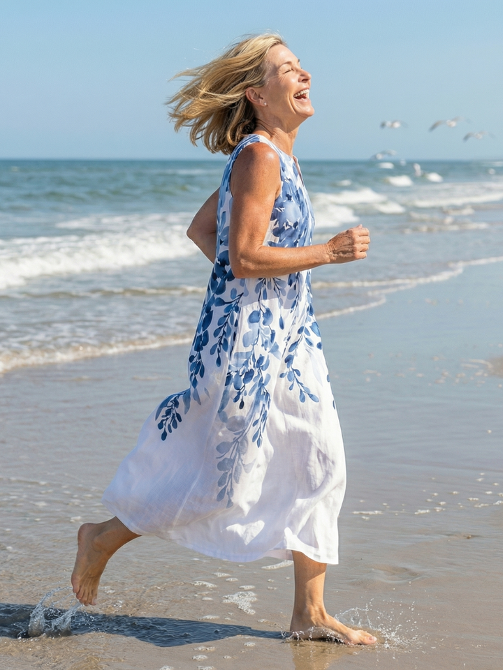 Happy woman running along the shore in a lightweight floral maxi dress