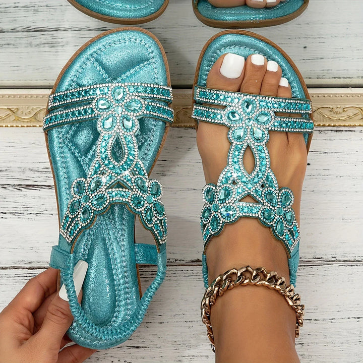 Lifestyle shot of feet wearing floral rhinestone strappy flat shoes