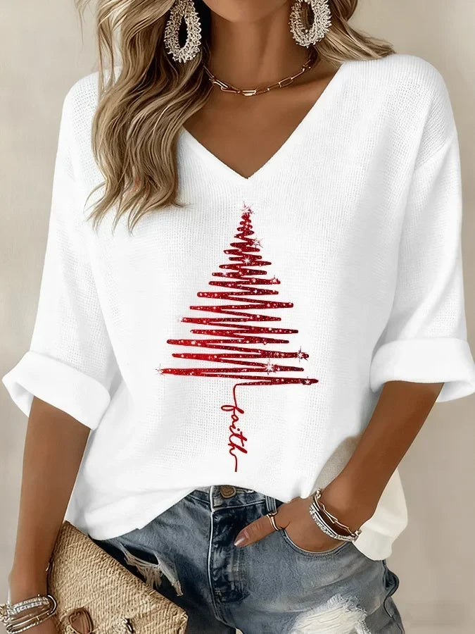 Woman wearing white Christmas printed V-neck knit top with red tree graphic