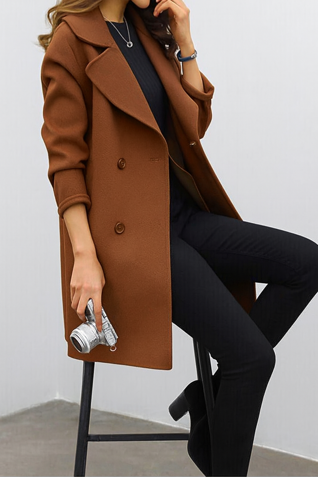 Close-up of a woman seated while wearing a brown double-breasted coat