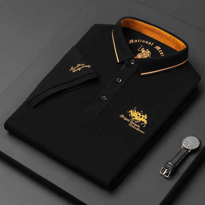 Black men's classic polo shirt folded with gold embroidery and wristwatch