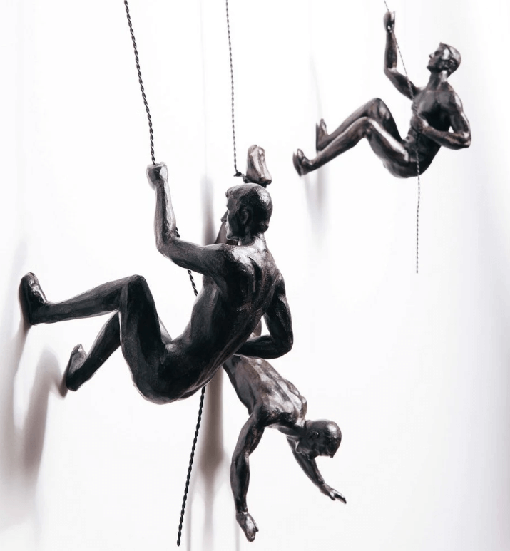 Multiple climbing figurines arranged together on a wall display