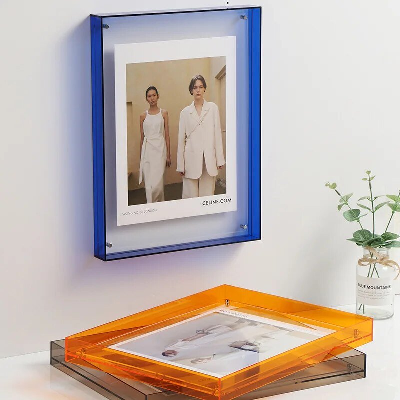 Blue acrylic photo frame mounted on a white wall above a desk