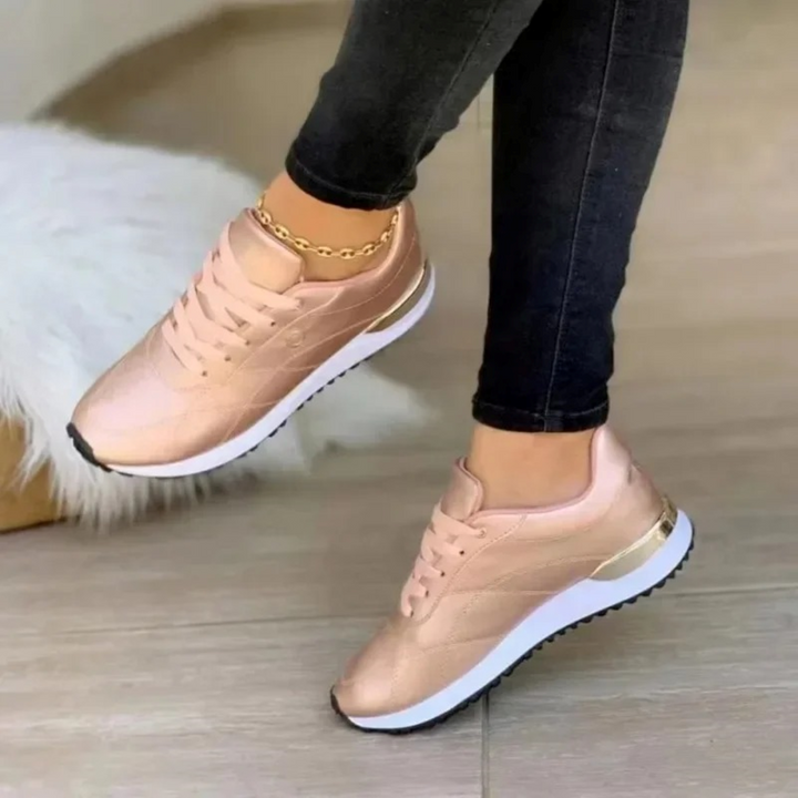 Woman wearing rose gold casual sneakers from a side angle