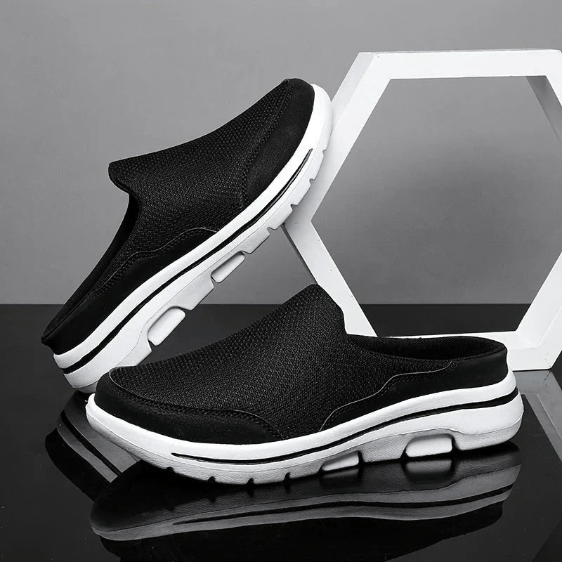 Black men's breathable comfort slippers displayed on a dark reflective surface