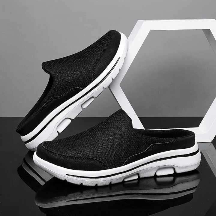 Black men's breathable comfort slippers displayed on a dark reflective surface