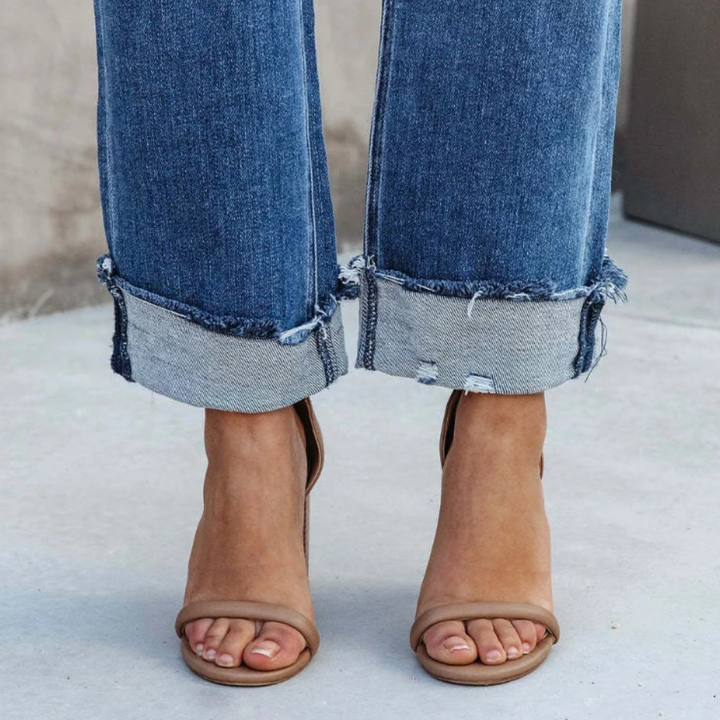 Close-up view of the rolled denim cuffs and footwear details