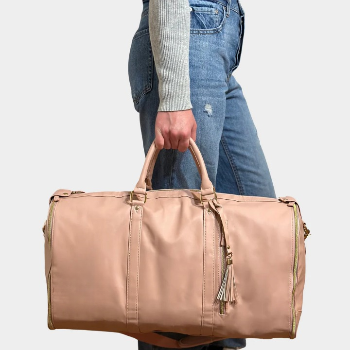 Model carrying the pink travel garment duffel bag by the handles