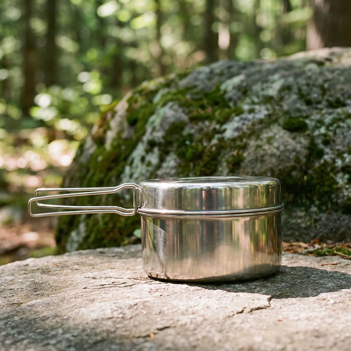 Compact stainless steel mess kit packed tightly and resting on a mossy rock in the forest