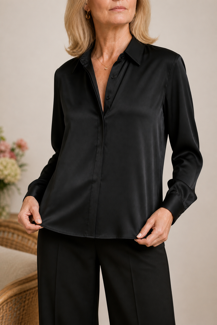A model wearing a black long-sleeve blouse with a concealed placket.