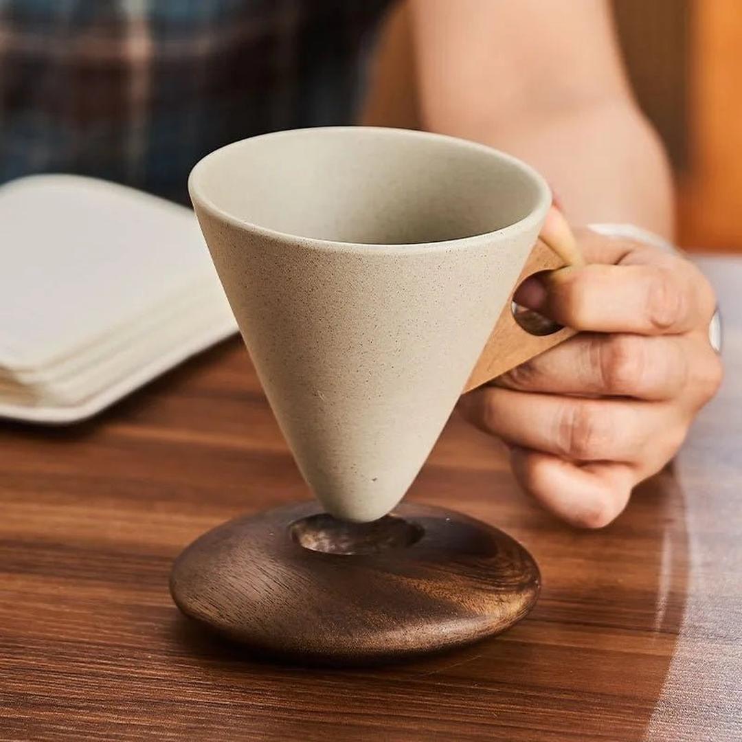 A conical coffee cup resting perfectly in its custom wooden coaster on a table