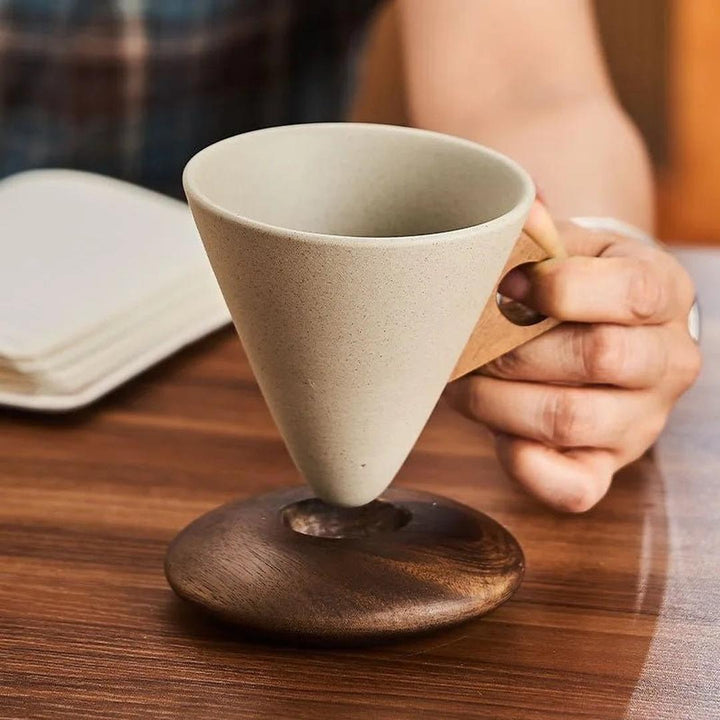 A conical coffee cup resting perfectly in its custom wooden coaster on a table