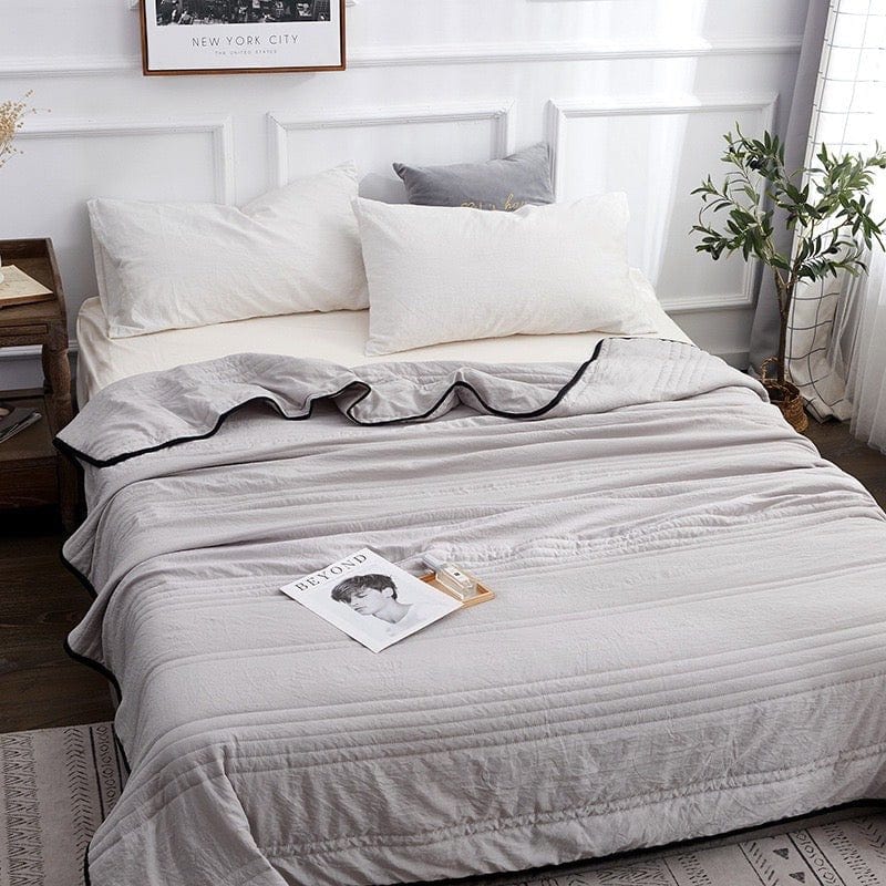 Gray cooling sleep blanket spread across a neatly made guest bed