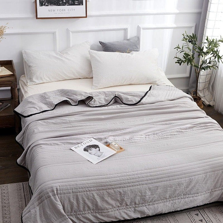 Gray cooling sleep blanket spread across a neatly made guest bed