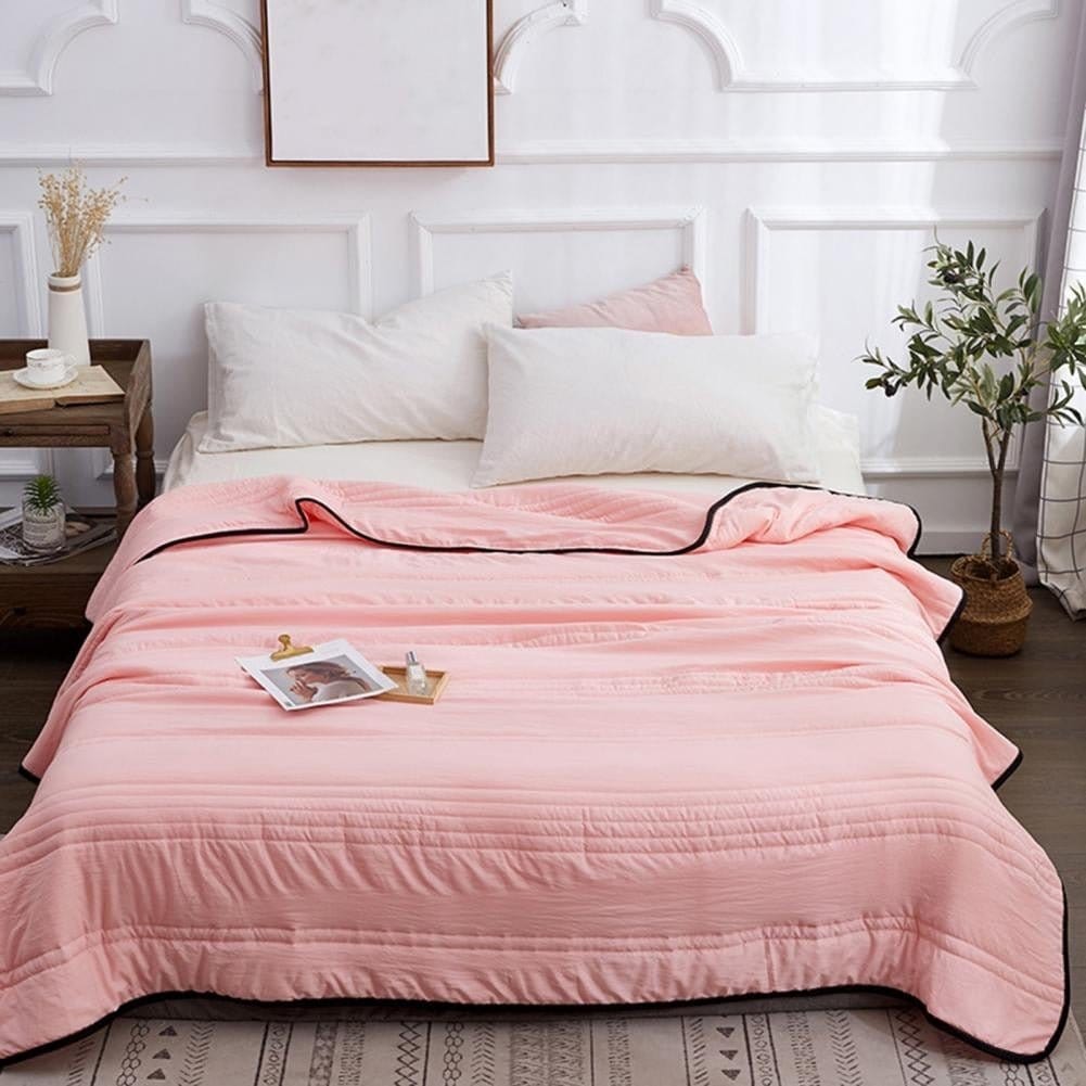 Pink cooling sleep blanket displayed on a comfortable bedroom bed