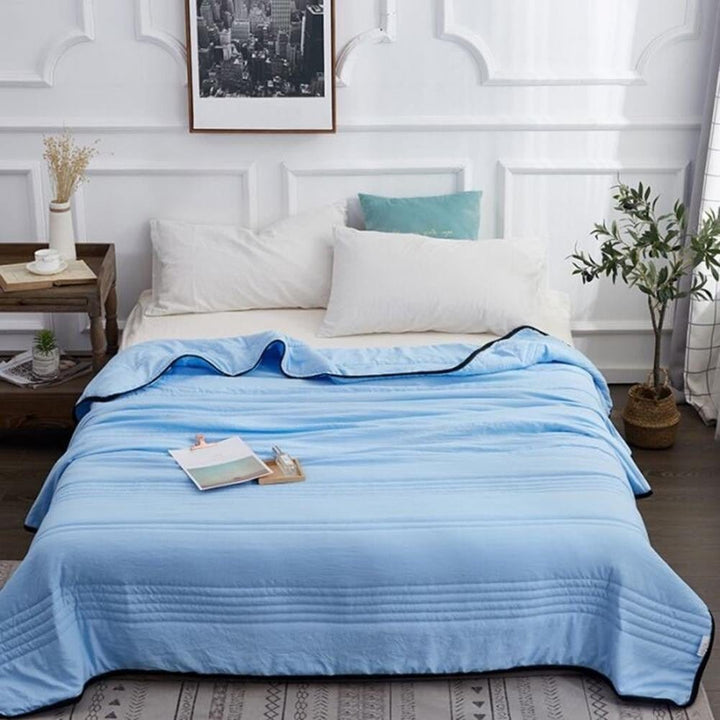 Cooling sleep blanket draped over a bed for hot sleepers