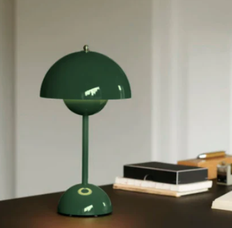 Green cordless retro LED table lamp placed on a dark desk with books