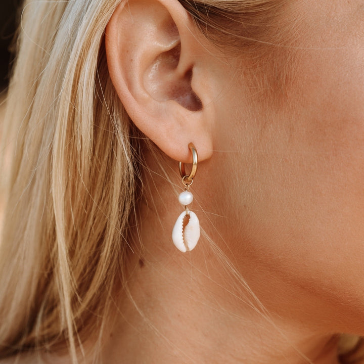 Flat lay of gold and silver boho seashell earrings with summer props