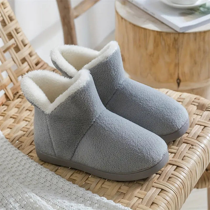 Gray cozy lined ankle boot slippers shown on a rustic woven chair
