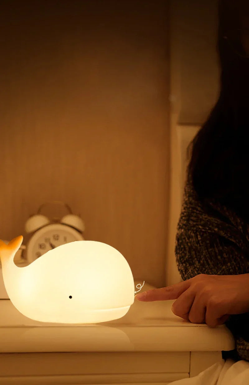 Child-friendly whale night light casting a warm glow in a dark bedroom
