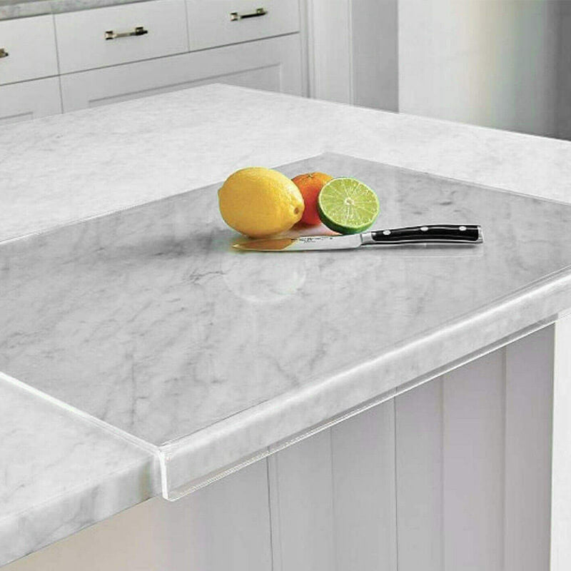 Clear acrylic chopping board resting on a marble kitchen island with fresh citrus fruit and knife