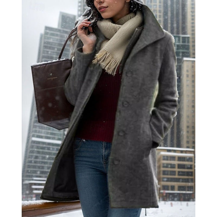 Woman wearing a gray turn-down collar trench coat during a snowy day in the city