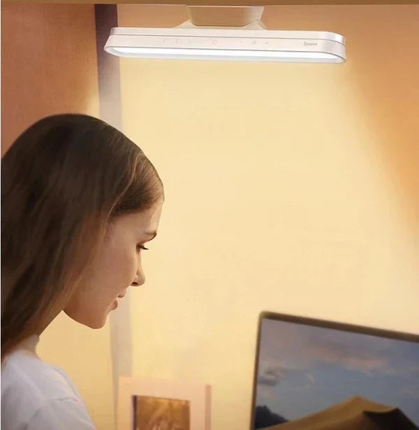 Modern minimalist LED desk lamp illuminating a workspace setup with warm light