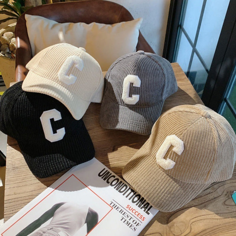 Assorted beige, grey, and black letter patch caps displayed together on a table