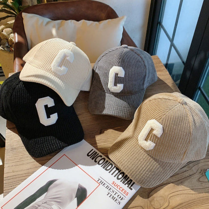 Assorted beige, grey, and black letter patch caps displayed together on a table