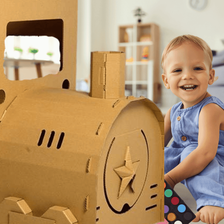 Smiling toddler playing near the assembled DIY cardboard locomotive building set