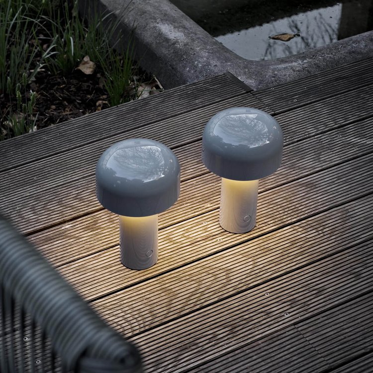 Two grey wireless mushroom table lamps glowing on an outdoor wooden deck