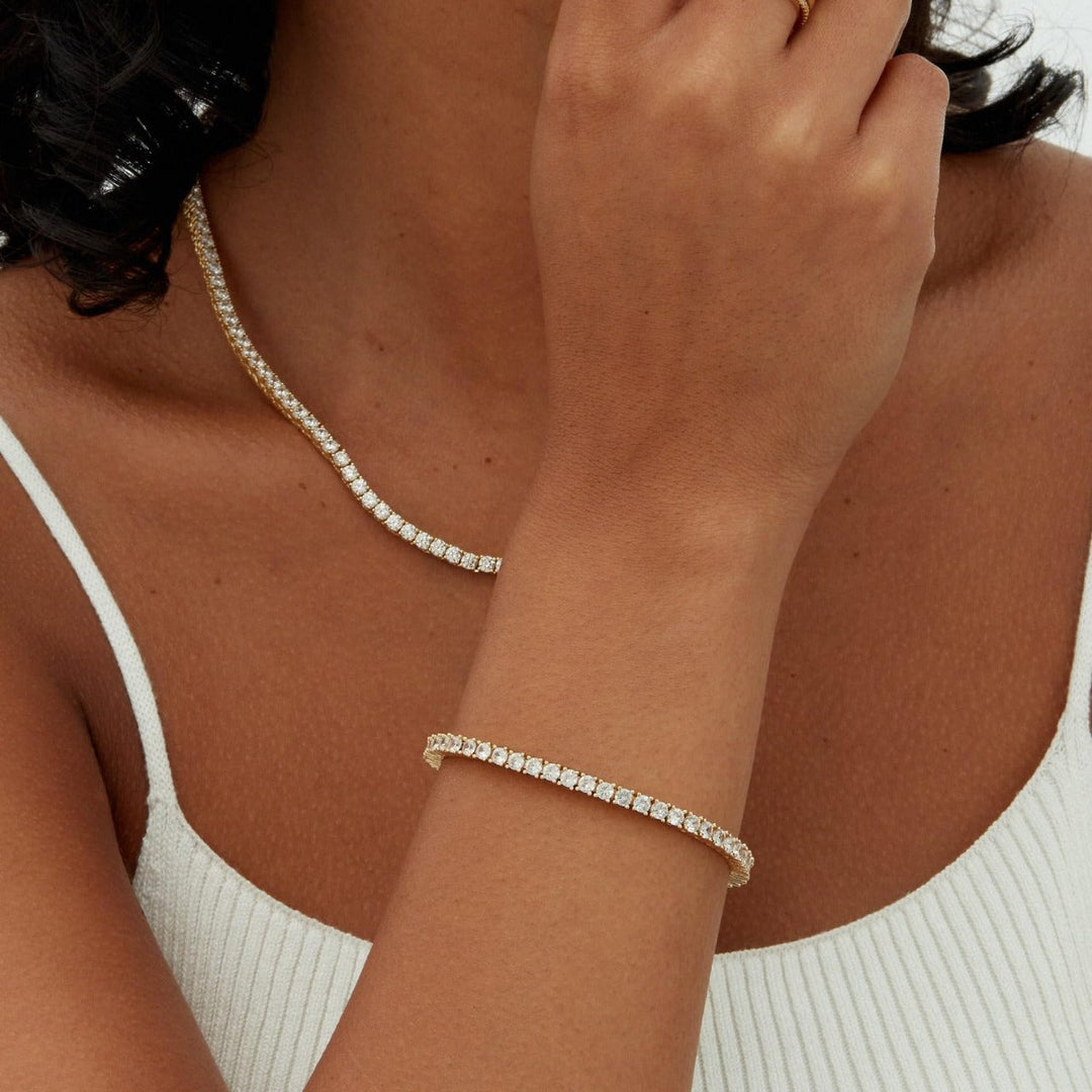 Close-up of a person wearing a gold single-row tennis bracelet on their wrist