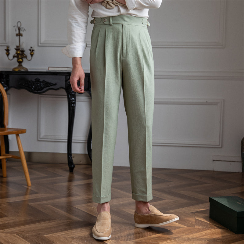 Man wearing sage green pleated cropped trousers with loafers in a classic interior
