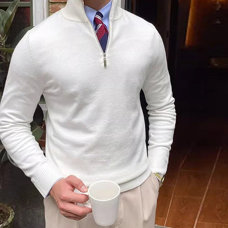 Man wearing a white quarter zip sweater holding a coffee cup