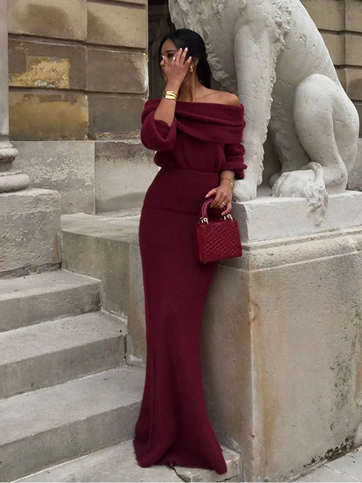 Full-length view of a woman posing against a stone wall in a red long-sleeve winter maxi dress