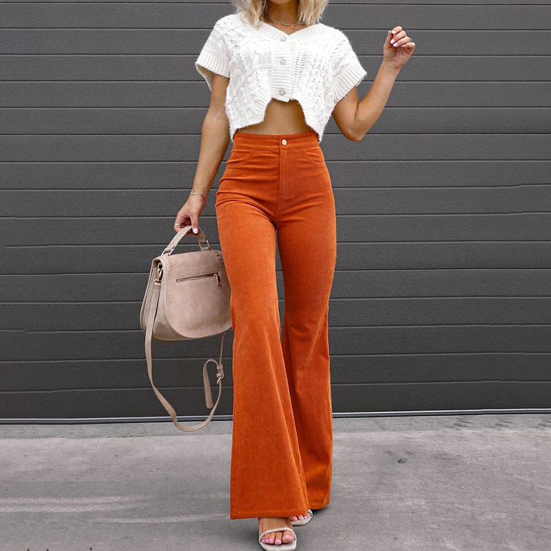 Model wearing orange high-waisted flared trousers with a white top and handbag