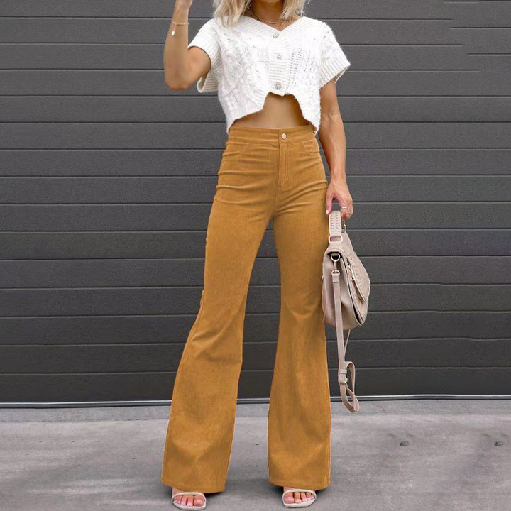 Model wearing khaki high-waisted flared trousers with a white top and handbag