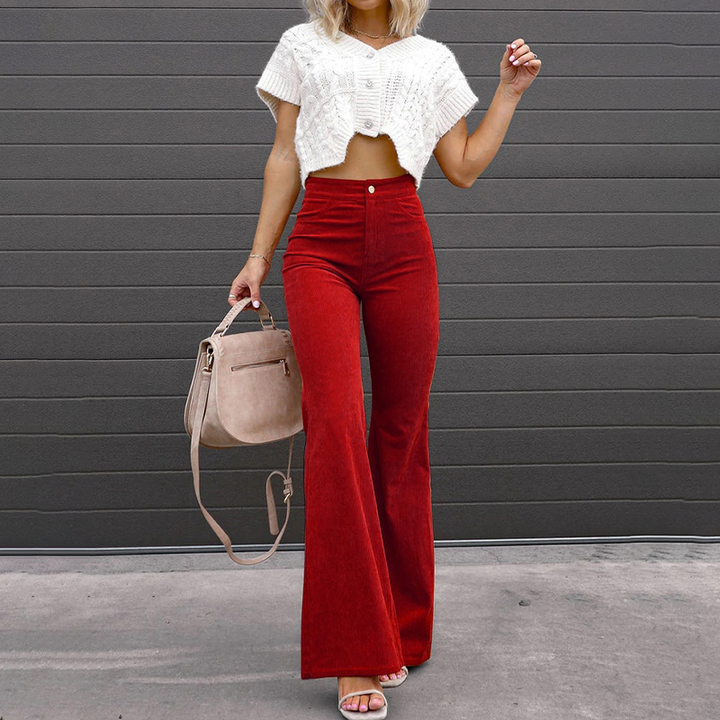 Model wearing red high-waisted flared trousers with a white top and handbag