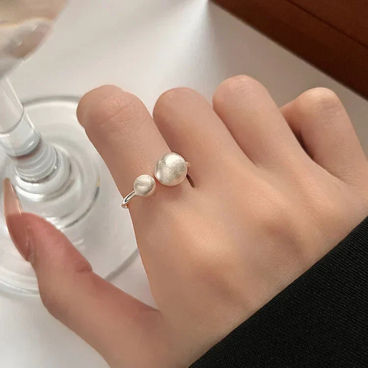 Women's brushed silver ring with connected pearls worn on finger