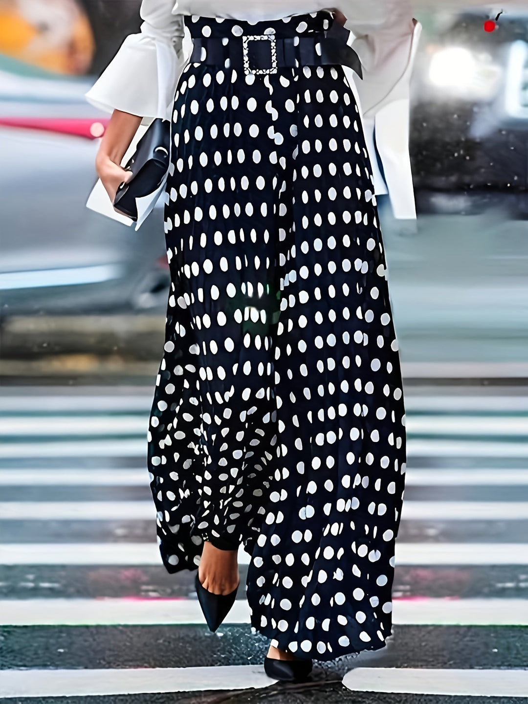 Woman wearing plus size black and white polka dot wide-leg trousers with a stylish belt walking on a street
