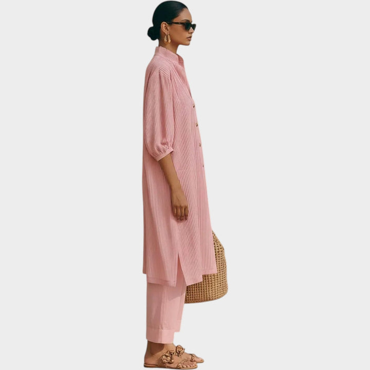 Side profile of a woman modeling the pink matching tunic and trousers set with sunglasses.