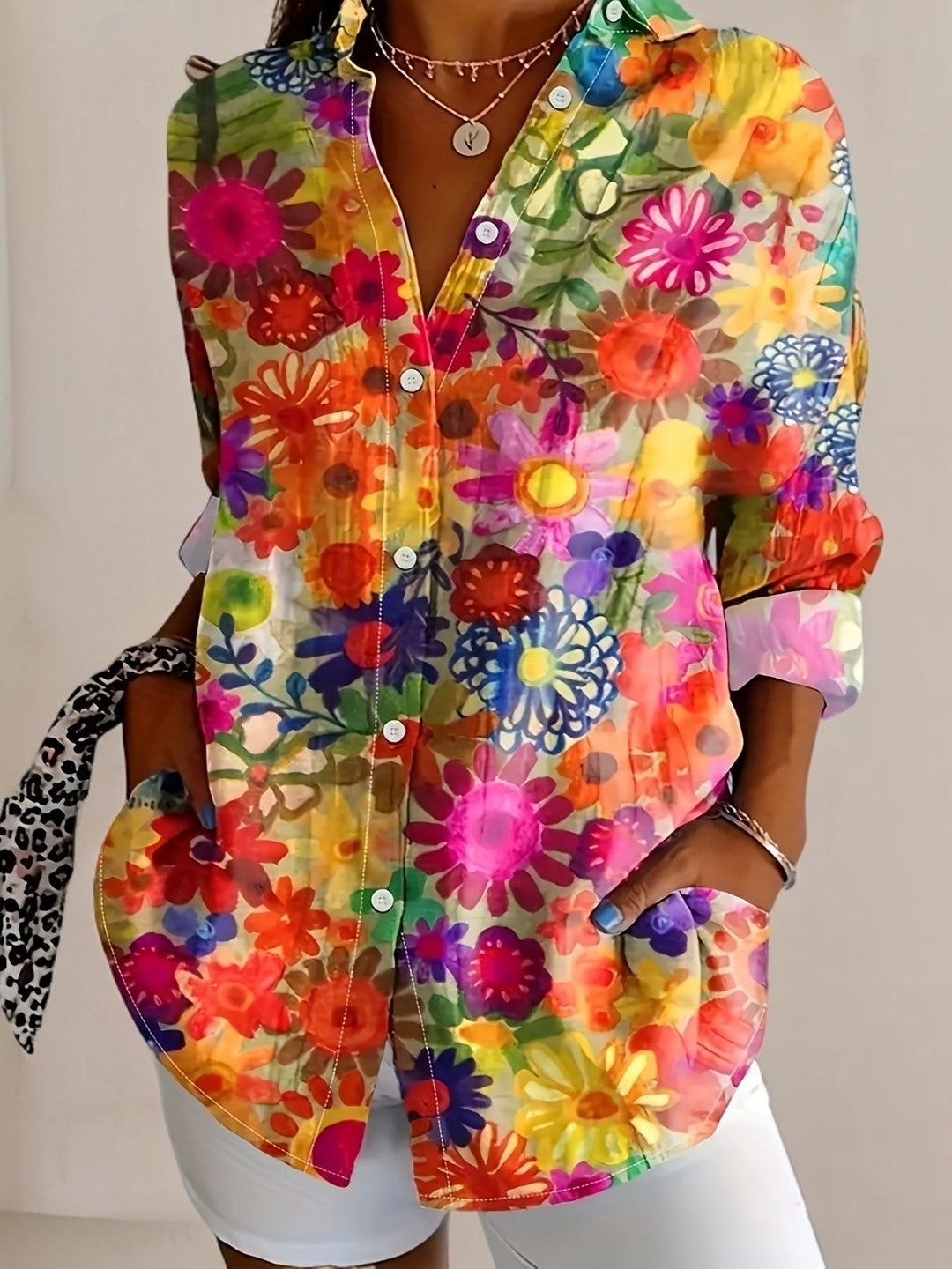 Woman wearing a vibrant floral button-front long sleeve blouse with front pockets