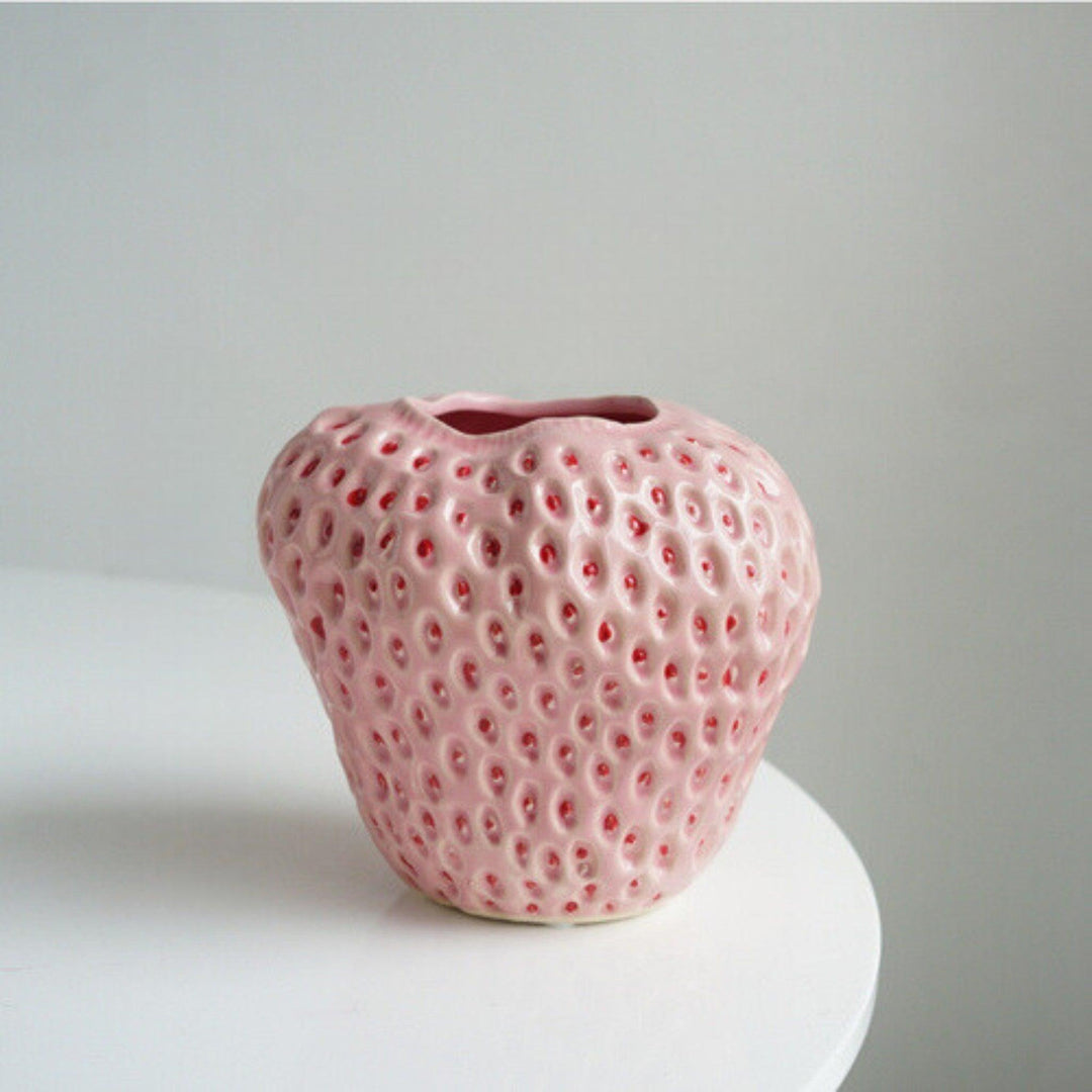 Pink ceramic strawberry vase displayed on a white table surface