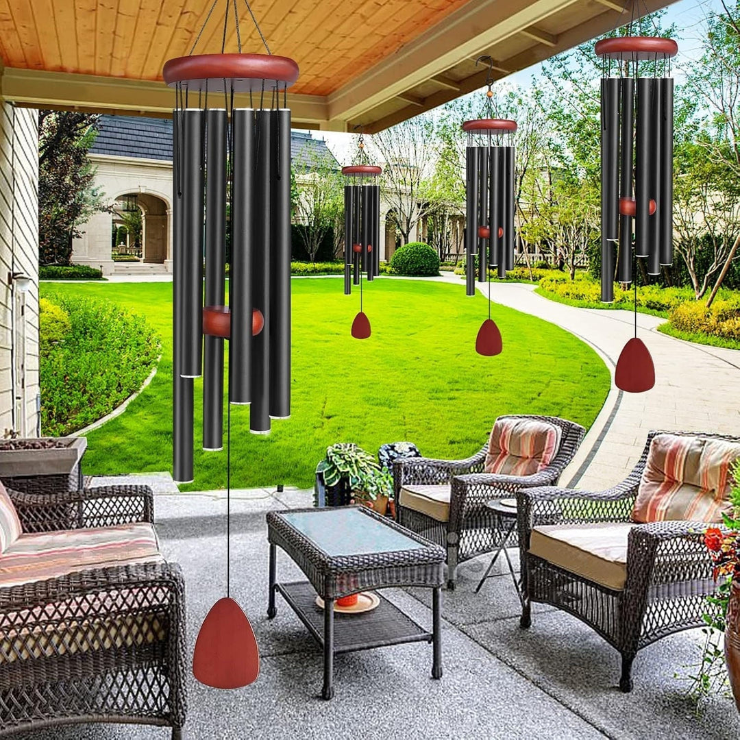Black deep tone aluminum wind chimes hanging on a patio with green garden background